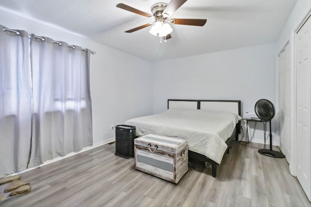bedroom with baseboards, light wood-style floors, and a ceiling fan