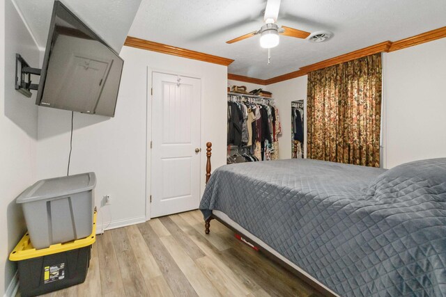 bedroom with a ceiling fan, wood finished floors, baseboards, visible vents, and ornamental molding
