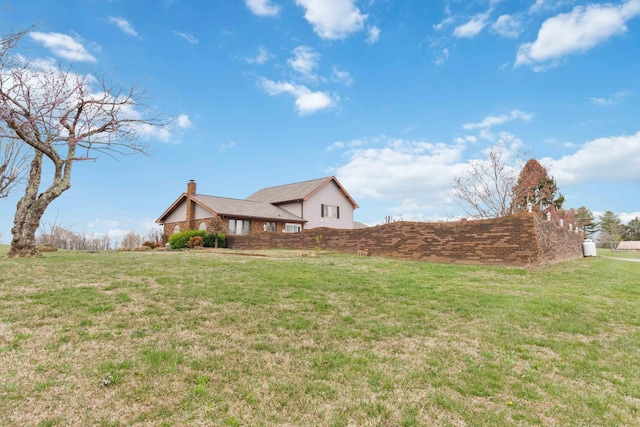 view of side of home with a lawn and a chimney