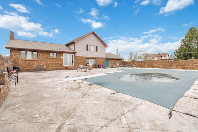 view of pool featuring fence, a diving board, and a patio area