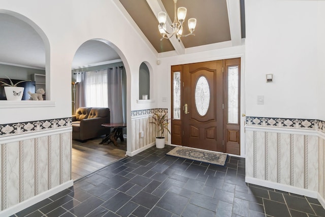 entrance foyer featuring a notable chandelier, ornamental molding, wainscoting, and stone finish flooring
