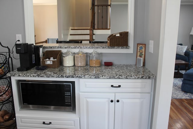 interior space featuring white cabinets, wood finished floors, and stone countertops
