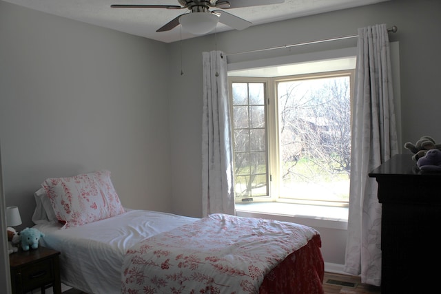 bedroom featuring wood finished floors, multiple windows, ceiling fan, and visible vents