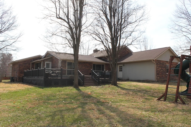 rear view of house featuring a playground, brick siding, a yard, and a wooden deck