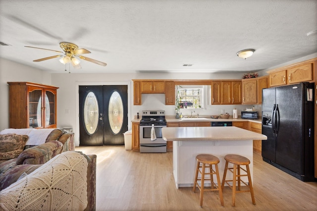 58 Mcclendon Ln, Russell Springs, KY 42642 - kitchen with black appliances, a sink, light wood-style floors, light countertops, and a textured ceiling