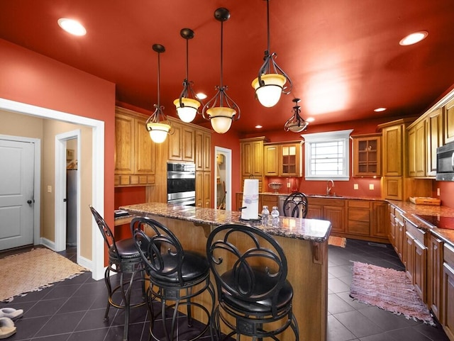 100 Mountain Enterprise Dr, Inez, KY 41224 - kitchen with dark tile patterned floors, a breakfast bar, double oven, a sink, and brown cabinets