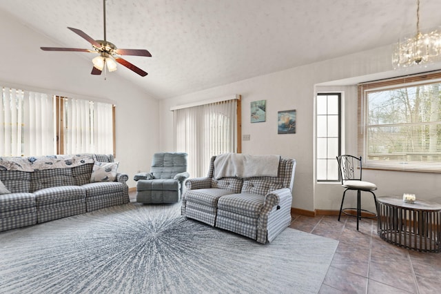 living room featuring vaulted ceiling, ceiling fan with notable chandelier, baseboards, a textured ceiling, and tile patterned floors
