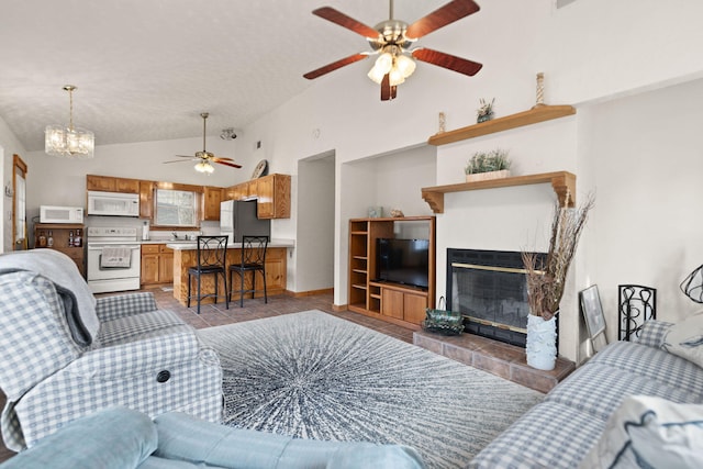 living room featuring light tile patterned floors, a fireplace, high vaulted ceiling, and ceiling fan with notable chandelier