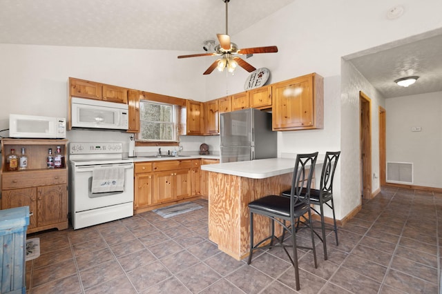kitchen featuring light countertops, a sink, a peninsula, white appliances, and visible vents