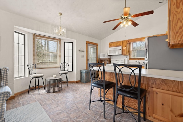 kitchen featuring a wealth of natural light, brown cabinets, a peninsula, and white appliances