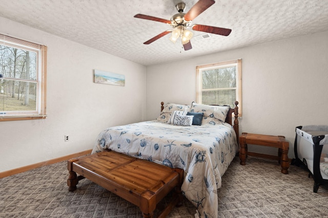 carpeted bedroom featuring baseboards, visible vents, a ceiling fan, and a textured ceiling