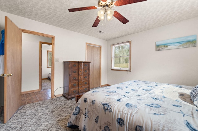 carpeted bedroom featuring a closet, a textured ceiling, visible vents, and tile patterned flooring