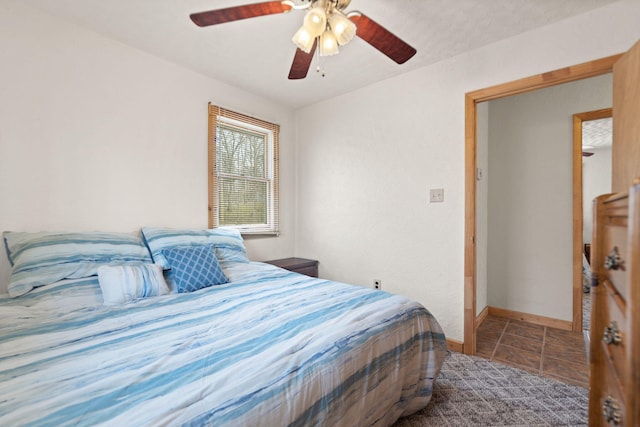 tiled bedroom featuring baseboards and ceiling fan