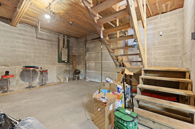 unfinished below grade area with a garage, concrete block wall, and stairway