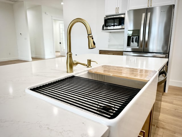 details featuring baseboards, a sink, white cabinetry, and appliances with stainless steel finishes