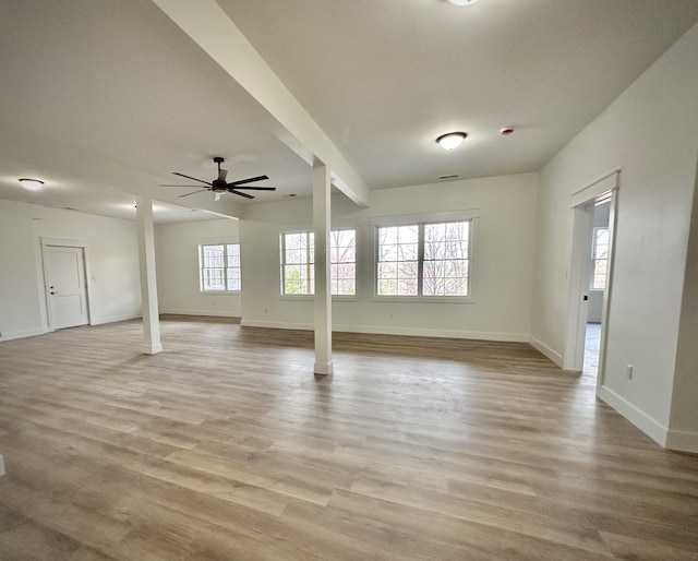 unfurnished living room featuring baseboards, decorative columns, ceiling fan, and light wood-type flooring