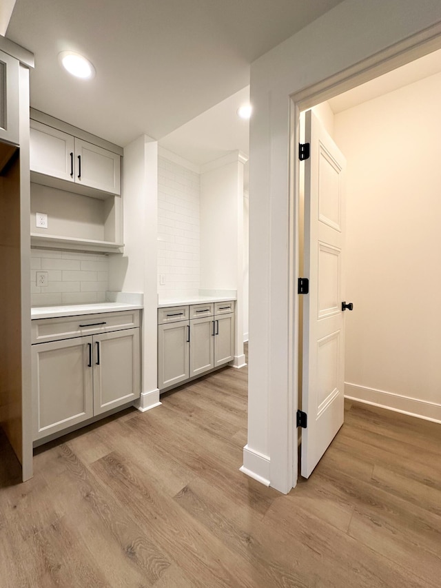 interior space with light countertops, backsplash, light wood finished floors, baseboards, and recessed lighting