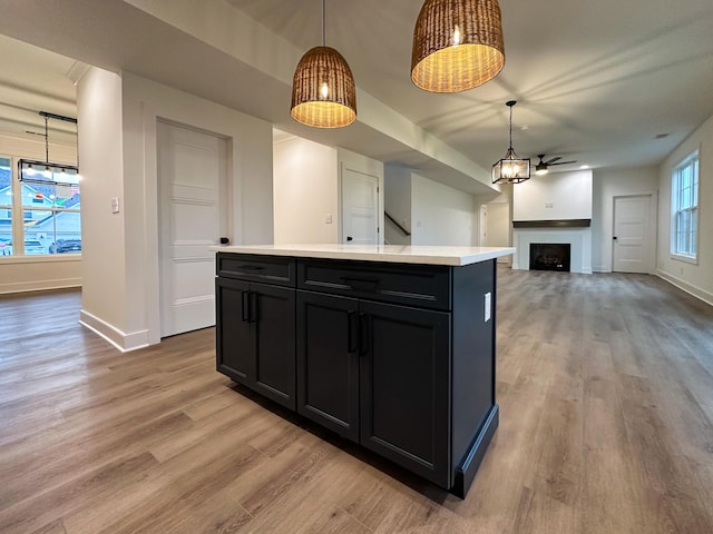 kitchen with a fireplace, light countertops, light wood-type flooring, and dark cabinets