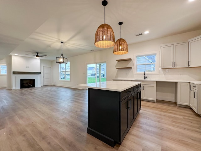 kitchen with decorative backsplash, light countertops, visible vents, ceiling fan, and light wood-style floors