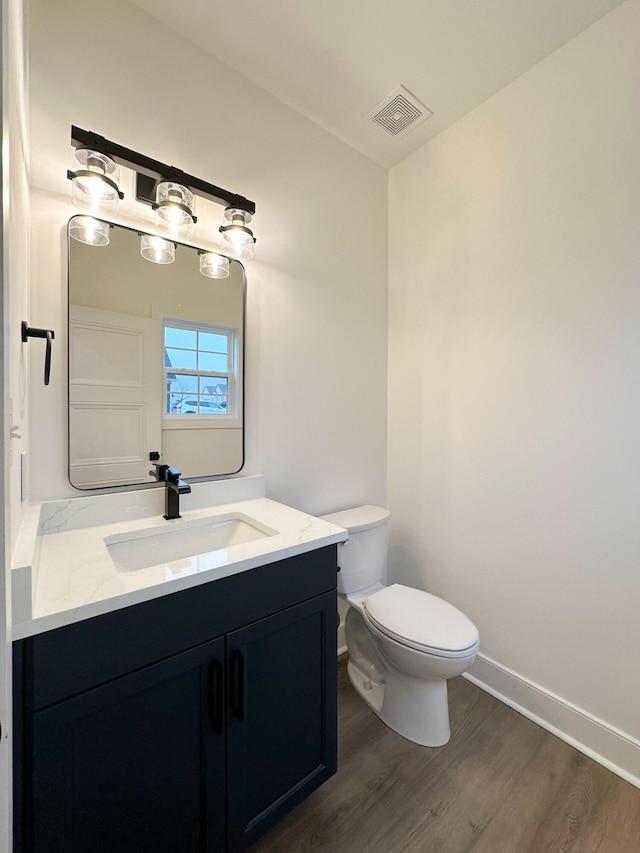 bathroom featuring vanity, toilet, baseboards, visible vents, and wood finished floors