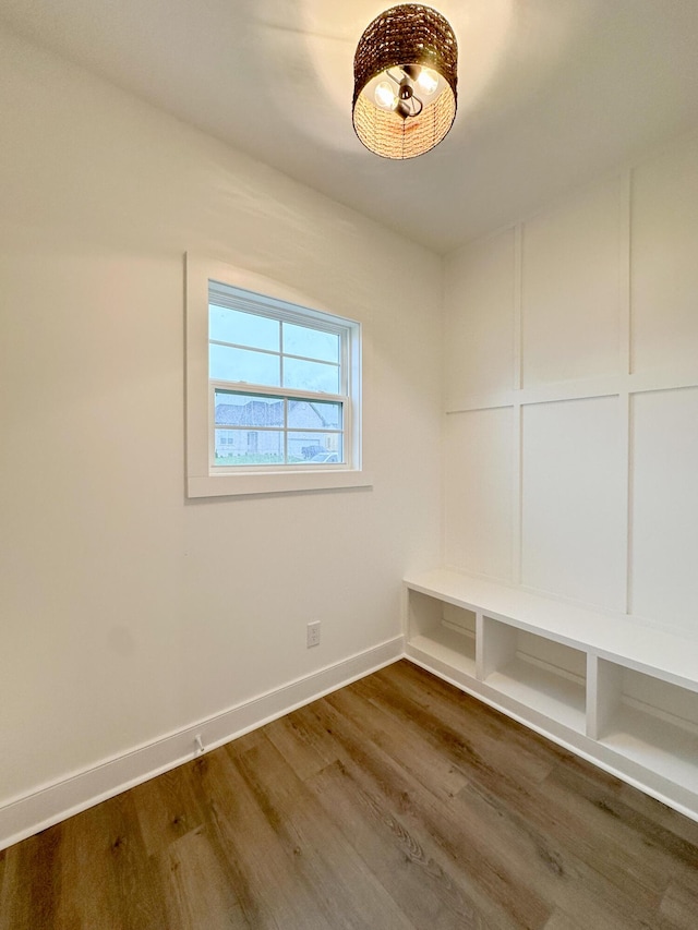 mudroom with dark wood-style floors, baseboards, and a decorative wall