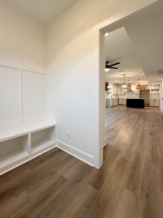 mudroom featuring baseboards, a ceiling fan, and dark wood-style flooring