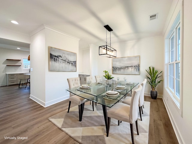 dining room featuring wood finished floors, ornamental molding, baseboards, and visible vents