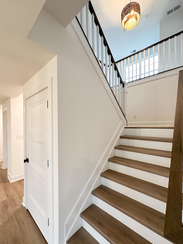 staircase featuring baseboards, visible vents, and wood finished floors