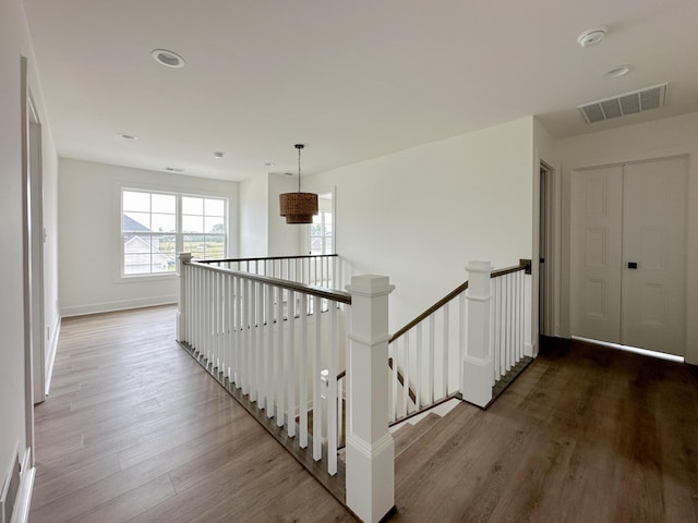 corridor featuring an upstairs landing, wood finished floors, baseboards, visible vents, and recessed lighting