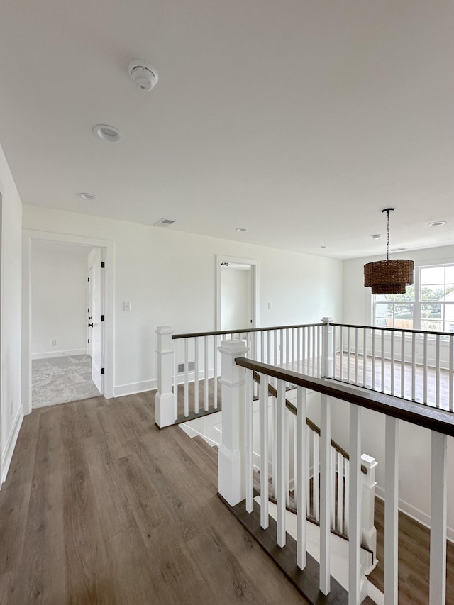 corridor featuring baseboards, an upstairs landing, and wood finished floors