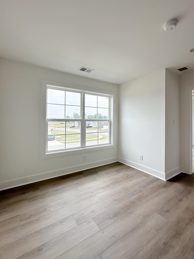 spare room featuring baseboards, visible vents, and wood finished floors