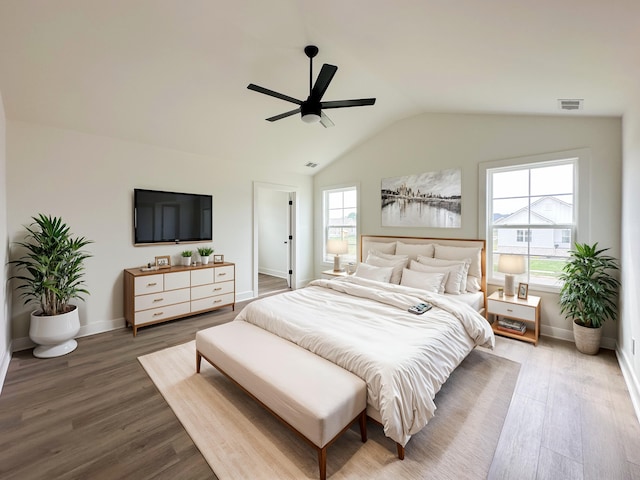 bedroom with a ceiling fan, wood finished floors, lofted ceiling, baseboards, and visible vents