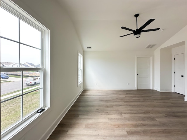 empty room featuring visible vents, ceiling fan, wood finished floors, lofted ceiling, and a healthy amount of sunlight
