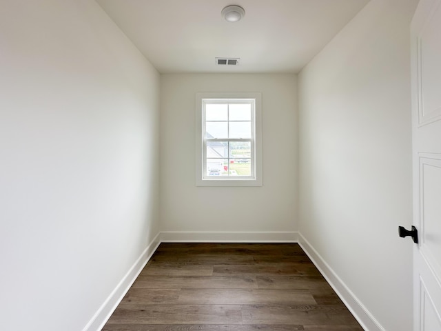empty room with baseboards, visible vents, and dark wood finished floors