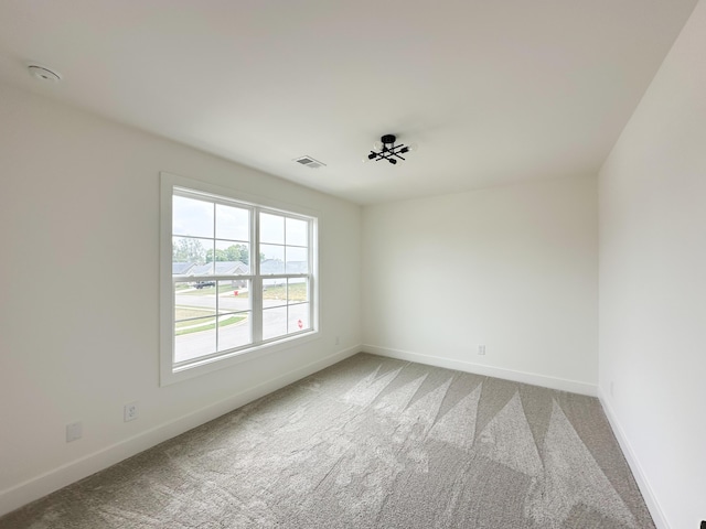 carpeted spare room with baseboards and visible vents