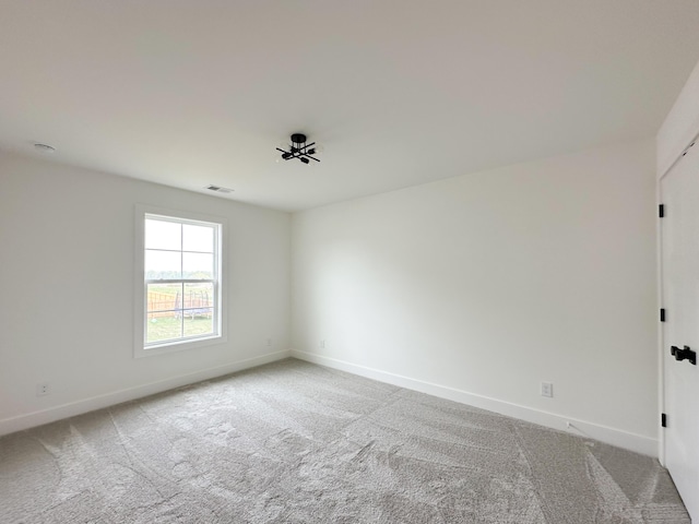 unfurnished room featuring light colored carpet, visible vents, and baseboards