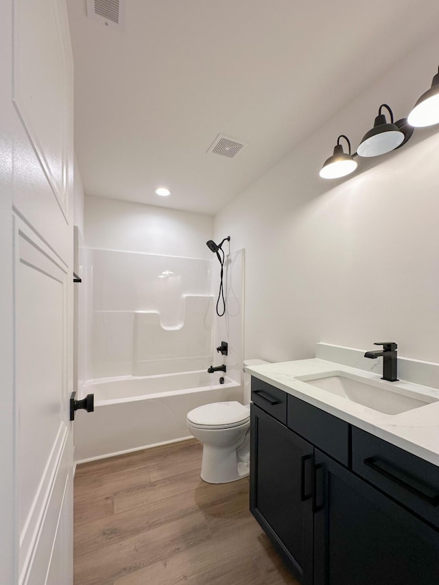 bathroom with vanity, toilet, bathtub / shower combination, visible vents, and wood finished floors