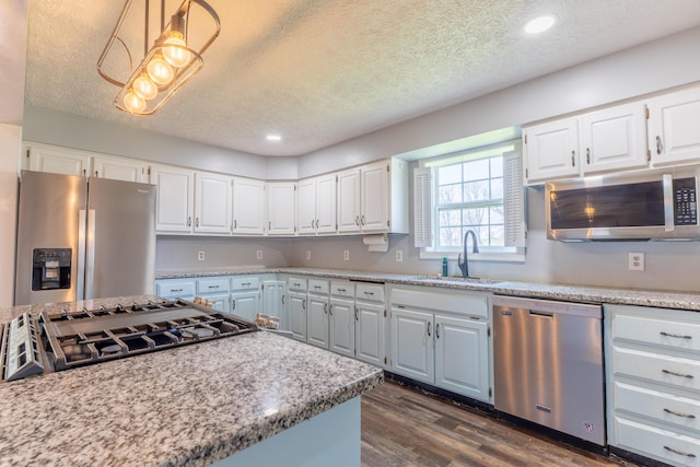kitchen featuring light countertops, a sink, appliances with stainless steel finishes, white cabinets, and dark wood-type flooring