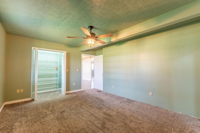 carpeted spare room with a textured ceiling and a ceiling fan