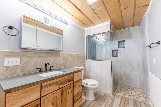 bathroom featuring vanity, tile walls, toilet, walk in shower, and visible vents