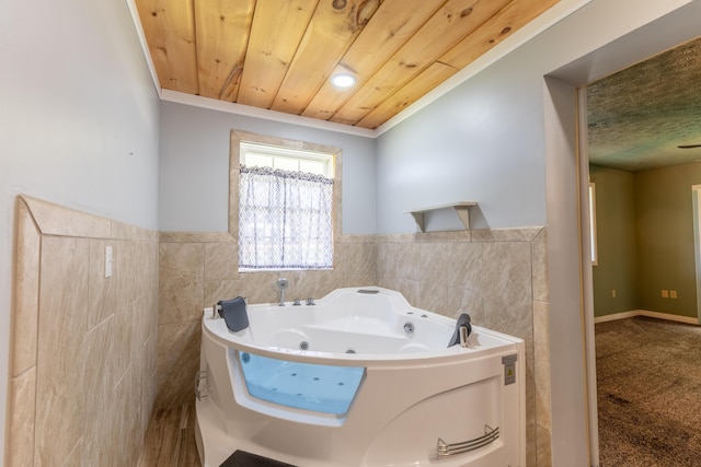 bathroom featuring tile walls, a wainscoted wall, a tub with jets, and wood ceiling