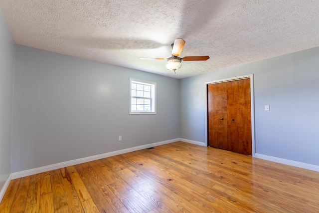 spare room featuring hardwood / wood-style floors, a ceiling fan, baseboards, and a textured ceiling