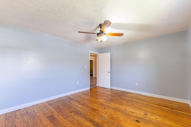 empty room featuring a textured ceiling, baseboards, ceiling fan, and wood finished floors