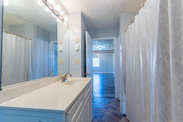 full bathroom with baseboards, vanity, and a textured ceiling