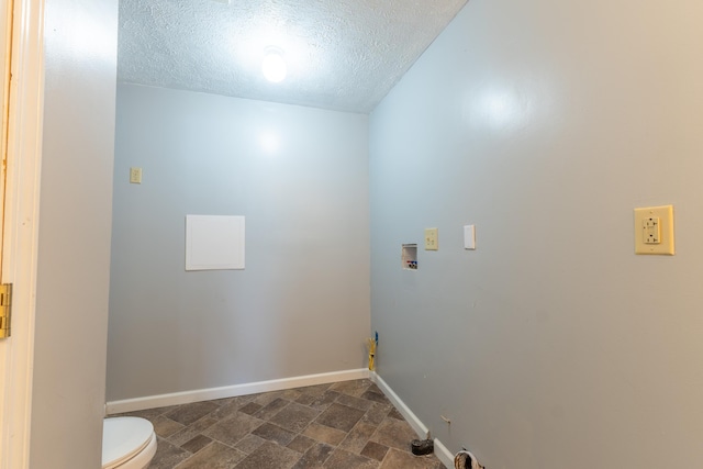 laundry area with stone finish floor, a textured ceiling, baseboards, and washer hookup