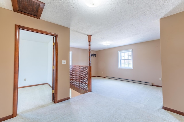 spare room with baseboards, carpet flooring, a textured ceiling, and a baseboard heating unit