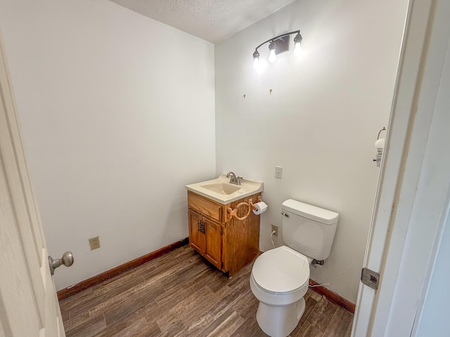 bathroom featuring toilet, a textured ceiling, baseboards, and wood finished floors