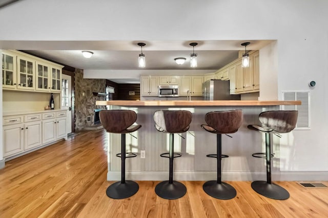 675 Indian Cave Subdivision Rd, Monticello, KY 42633 - kitchen featuring appliances with stainless steel finishes, light wood finished floors, baseboards, a peninsula, and a kitchen breakfast bar