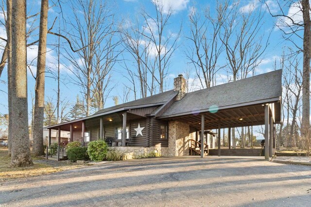 675 Indian Cave Subdivision Rd, Monticello, KY 42633 - log cabin featuring a chimney, log siding, a carport, a shingled roof, and driveway