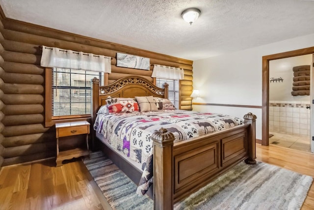 675 Indian Cave Subdivision Rd, Monticello, KY 42633 - bedroom featuring log walls, light wood-style floors, a textured ceiling, a wainscoted wall, and ensuite bath